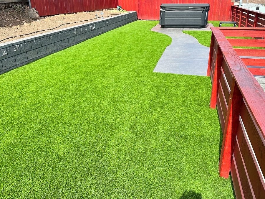 Artificial turf lawn with a stamped concrete path and red horizontal fence
